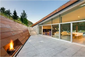 Corten clad wall for the sunken lounge inside the mountain home with green roof